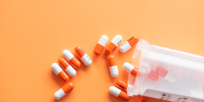 Assorted prescription medication bottles and pills arranged on a pharmacy shelf